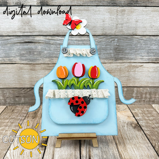 Decorative shelf sitter in the shape of an apron - interchangeable and featuring a spring add-on with tulips, a lady bug, a daisy and a butterfly.