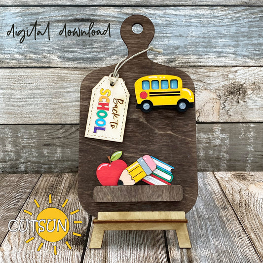 Digital download for a faux cutting board shelf decor featuring a Back to school add on with a School bus, an apple, pencil, stack of books, and a tag with the text 'Back to school'.