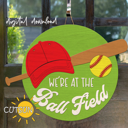 Digital download for a door hanger featuring a baseball cap, a bat, a baseball and the text 'We're at the Ball field'.
