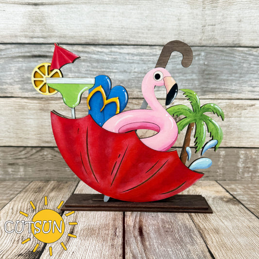 A colorful digital image of a Beach Vibes SVG add-on which includes a pink flamingo float, a tropical cocktail with a lemon slice and umbrella, palm tree, flip flops, and water splash elements, designed to be cut out and assembled with an upside-down umbrella for shelf decor.