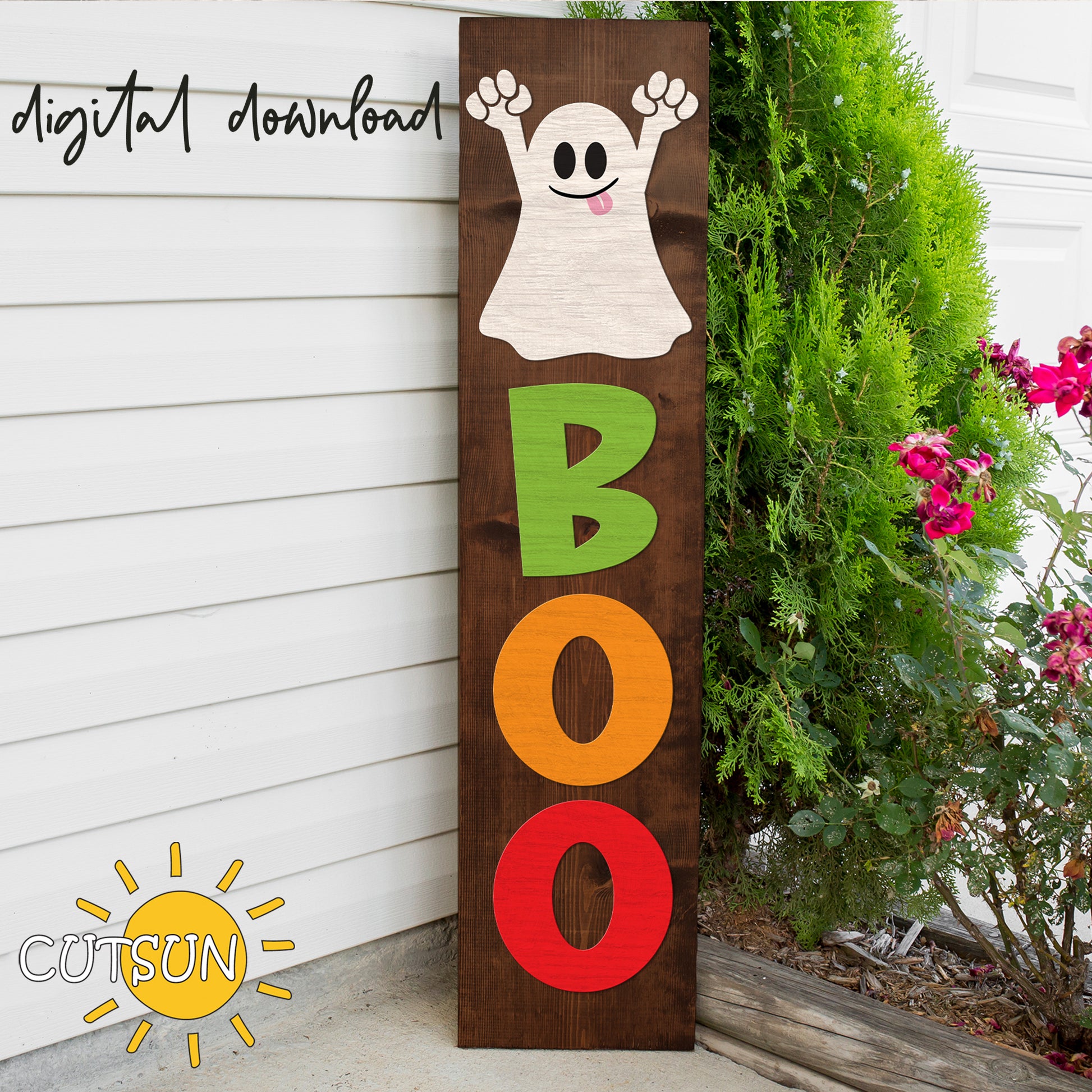 A vertical porch sign featuring a cute ghost with the word 'BOO' in Halloween colors, placed on a porch with flowers on either side.