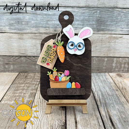 A digital image showing a wooden cutting board with a cute Easter bunny decoration, along with other Easter-themed elements like eggs and a tag.