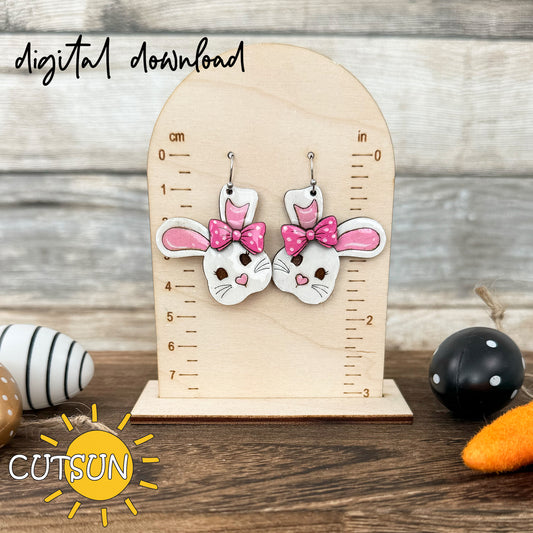 A digital rendering of a bunny-shaped earring with a floral pattern, displayed on a wooden stand, with Easter decorations in the background.