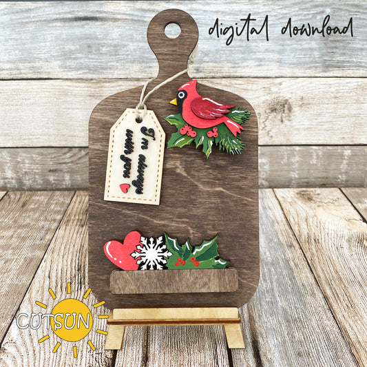Digital download for a faux cutting board shelf decor featuring Christmas cardinal, a heart, a snowflake and holly berry, and a tag with the text 'I'm always with you'.