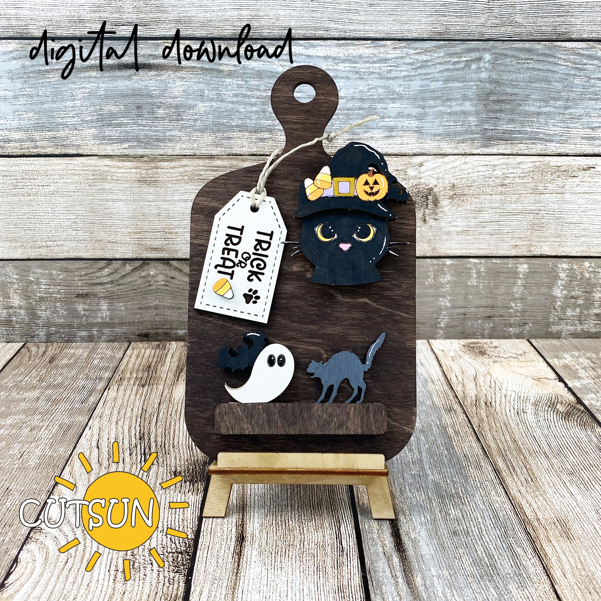 A digital download image showing a laser cut file for a Halloween themed cutting board decor, featuring a cat with a witch's hat and candy corns, a Jack-O-Lantern, and a bat on a wooden surface.