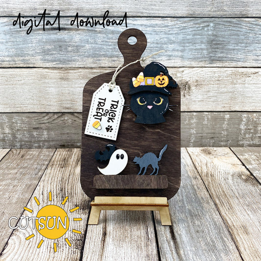 A digital download image showing a laser cut file for a Halloween themed cutting board decor, featuring a cat with a witch's hat and candy corns, a Jack-O-Lantern, and a bat on a wooden surface.