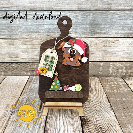A digital download image showing a laser cut file for a Christmas themed cutting board decoration, featuring an adorable puppy wearing a Santa's hat and other festive elements.