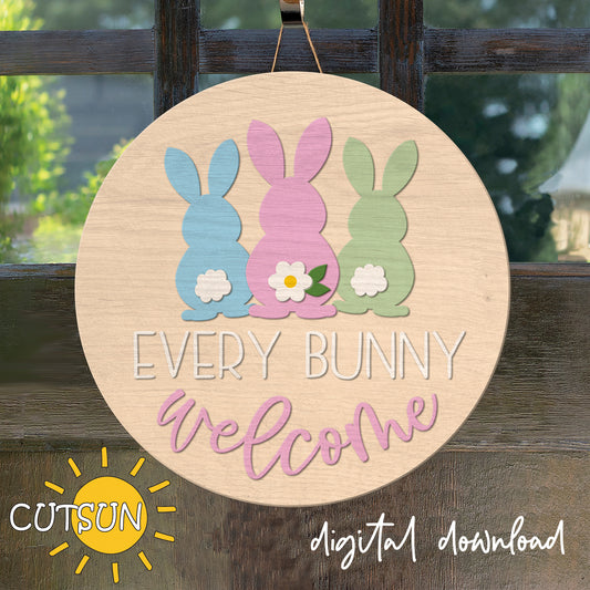 Decorative sign with three colorful bunnies and 'Every Bunny Welcome' text on a wooden background.