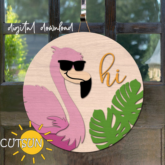 Circular wooden sign with a flamingo, sunglasses, and 'hi' text on a wooden surface.