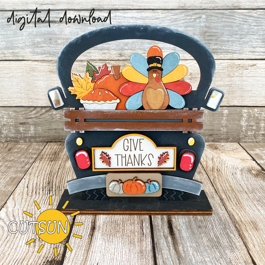 A digital image showing a decorative Thanksgiving-themed item, featuring a turkey with a pilgrim hat, pumpkin pie, fall leaves, and three pumpkins, labeled 'Give Thanks'.