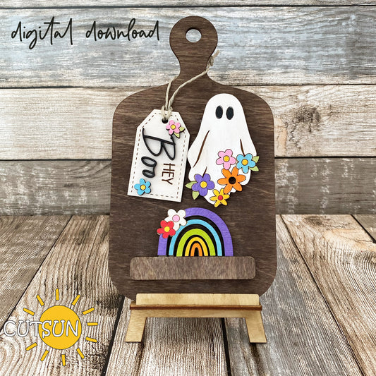 A digital download image showing a wooden cutting board with a decorative ghost, flowers, and a rainbow add-on, labeled 'Hey Boo'.