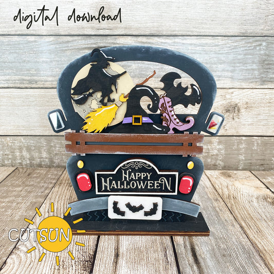 A decorative truck-shaped sign with a 'Happy Halloween' message, featuring silhouettes of a witch, a broom, a hat, a bat, and a shoe, and Halloween-themed embellishments.