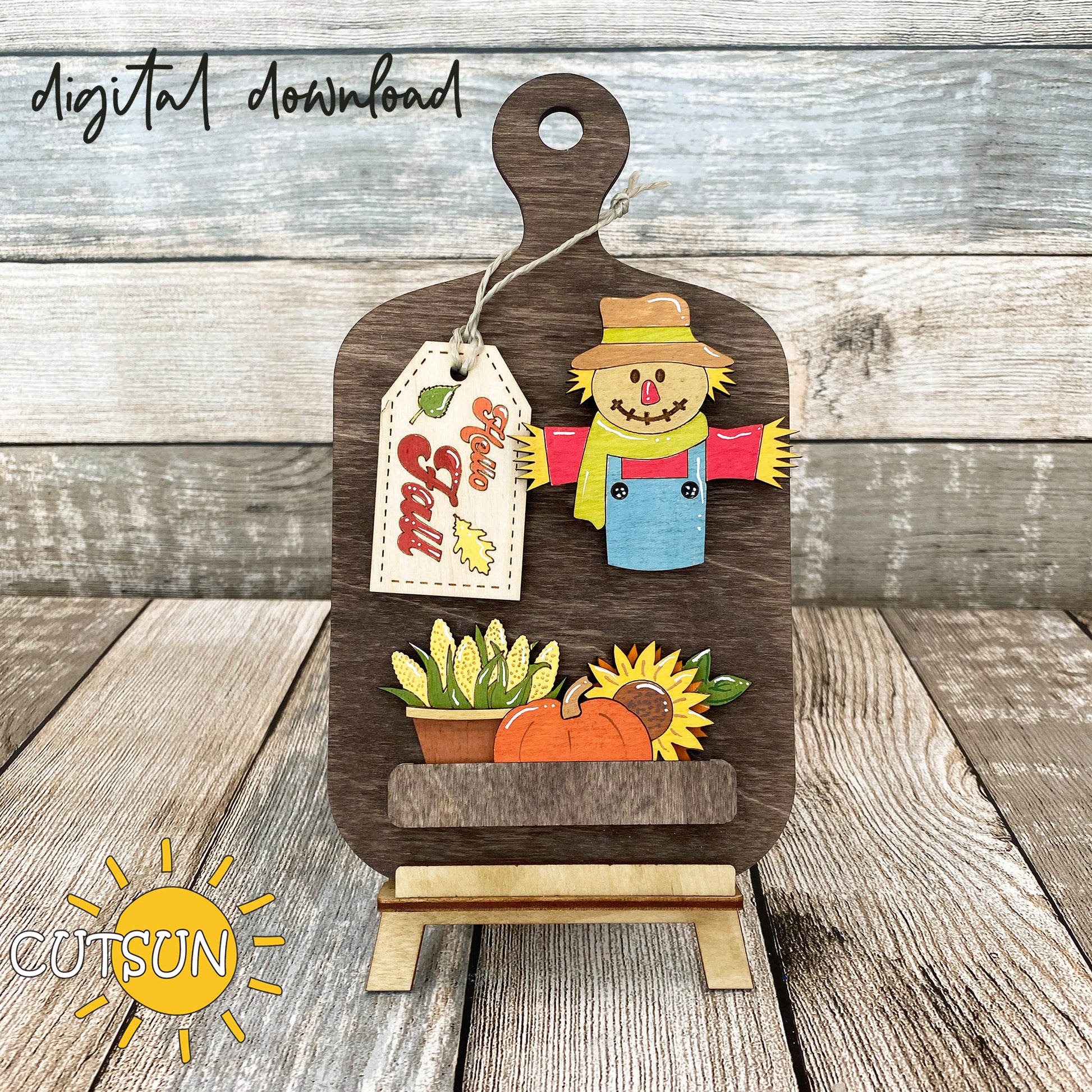 A digital download image showing a wooden cutting board decoration with a scarecrow, pumpkin, sunflower, and a 'Hello Fall' tag.