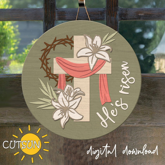 Decorative sign with cross, lilies, and 'He's Risen' text on a wooden background.