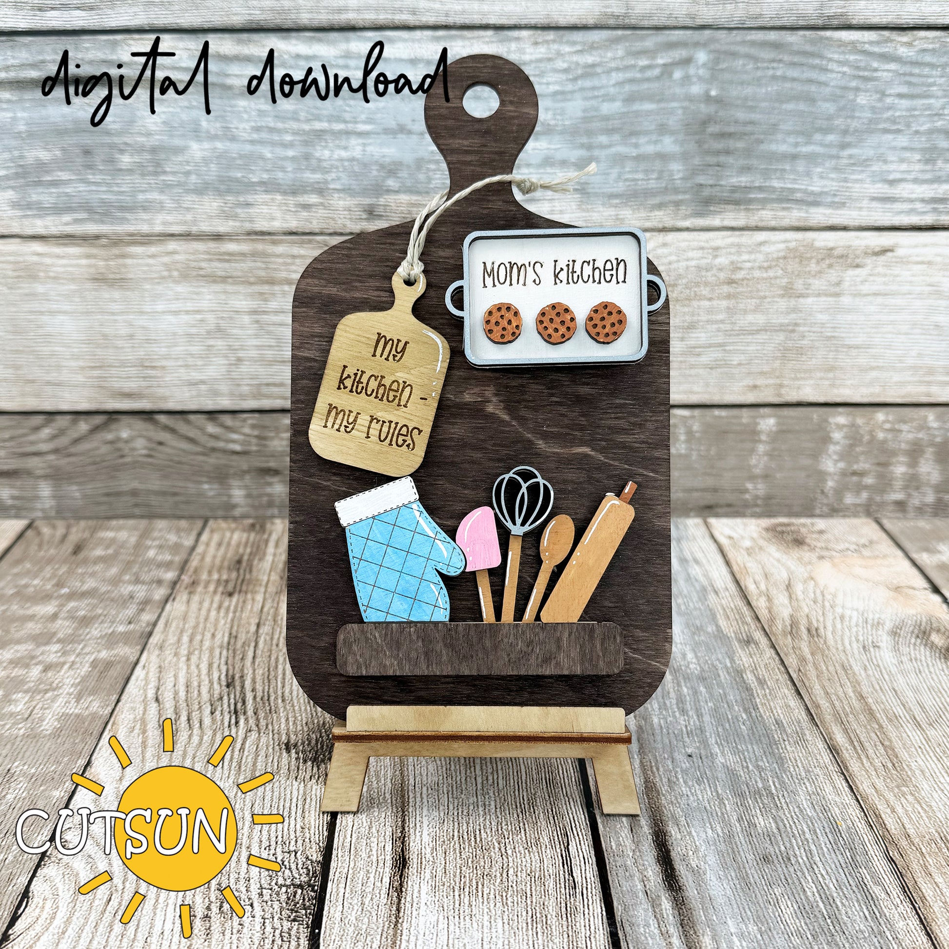 A digital representation of a cutting board decor set with interchangeable kitchen-themed elements such as a cookie sheet, oven glove, and kitchen utensils.