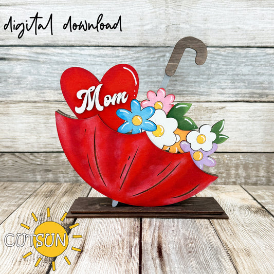 A digital download for a Mother's Day themed umbrella-shaped shelf sitter with the word 'Mom' and spring flowers designed for laser cutting.