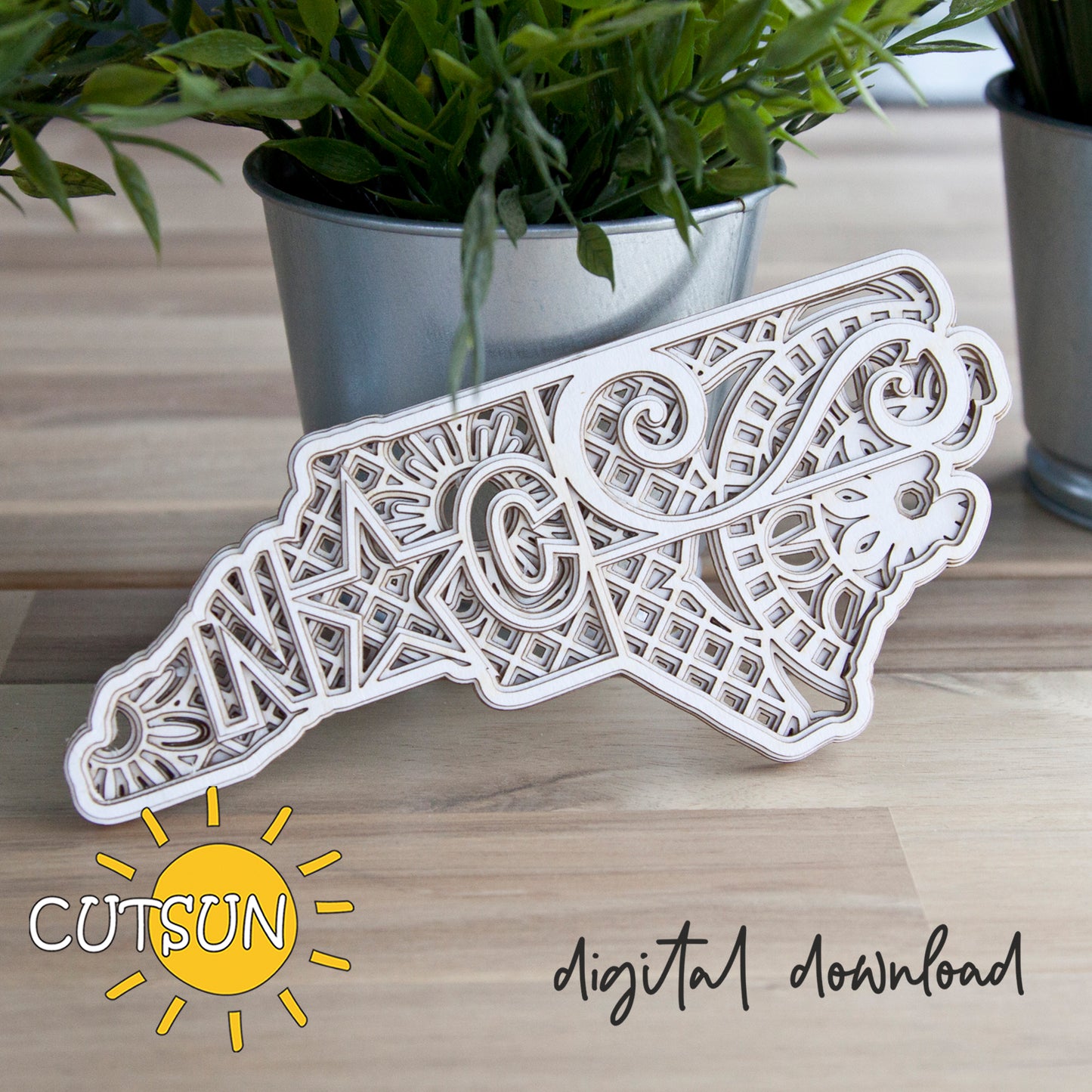 Decorative laser-cut paper cutout of a bear with intricate patterns on a wooden surface, featuring the Cutsun logo.