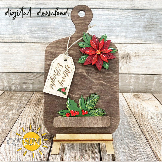 A digital image of a laser-cut Christmas-themed cutting board decoration, featuring a poinsettia flower, holly berries, and pine tree branches, with a tag that reads 'Merry & Bright'.