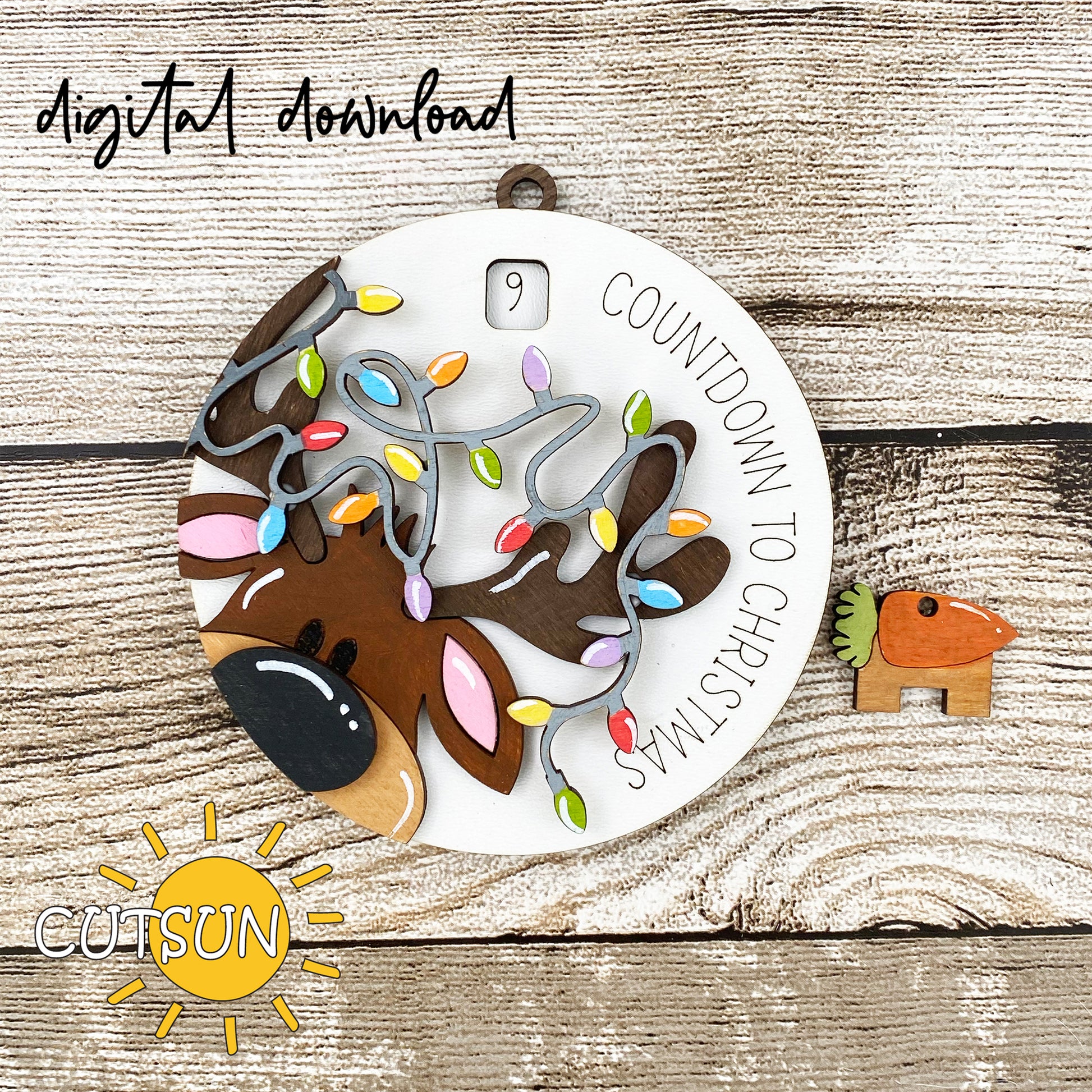 A digital download image showing a circular Christmas ornament with a reindeer and Christmas lights countdown, along with a small wooden heart with a carrot design.