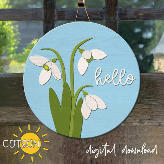 Circular sign with snowdrop flowers and 'hello' text on a wooden background, featuring the CUTSUN logo.