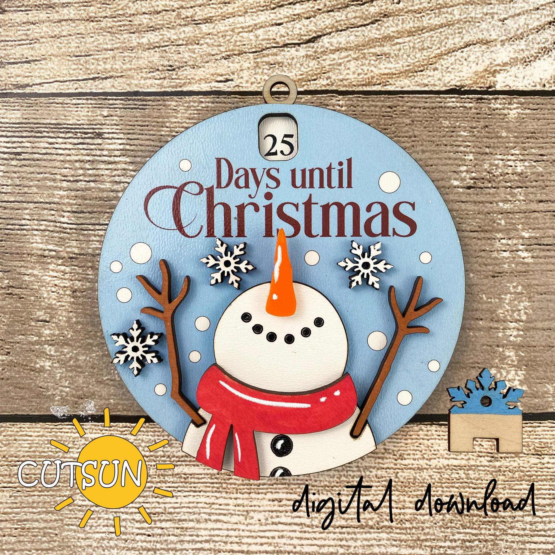 A digital illustration of a circular Christmas ornament with a snowman, snowflakes, and the text '25 DAYS UNTIL CHRISTMAS'.