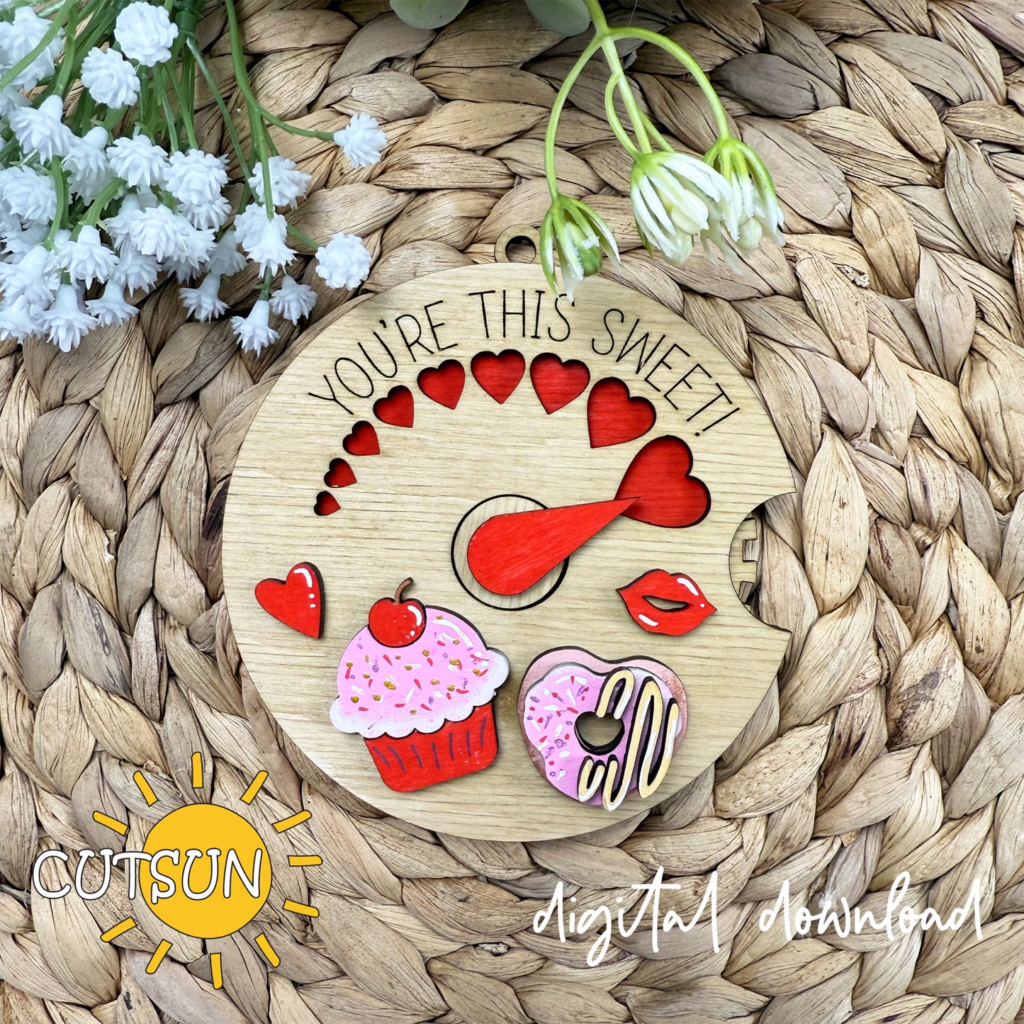 A digital image showing a round ornament SVG design with the text 'You're this sweet!' and various decorative elements such as hearts, a cupcake, a doughnut, and lips, indicating a Valentine's day theme.