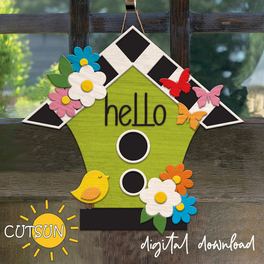 Decorative door hanger shaped like a birdhouse with flowers and butterflies on a wooden background.
