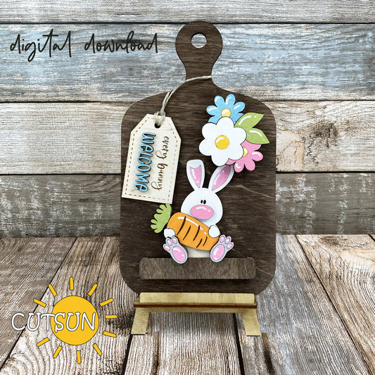 A digital rendering of a cutting board decor with an Easter theme, featuring an Easter bunny, carrots, and flowers.