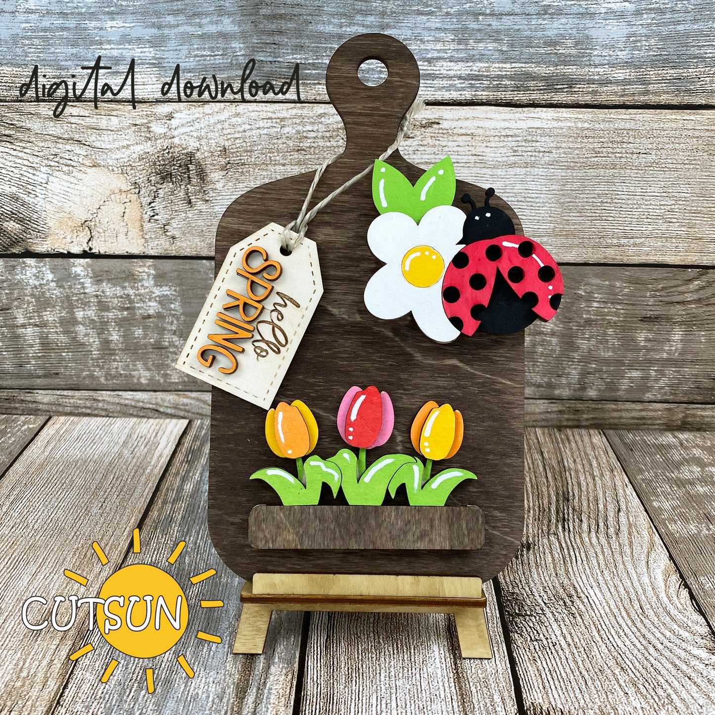 Digital download for a faux cutting board shelf sitter featuring a daisy, lady bug, three tulips and a tag with the text 'hello Spring'.