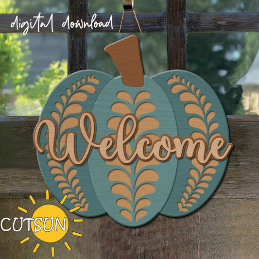 A digital image showing a fall-themed door hanger with a pumpkin design and the word 'WELCOME' in a decorative font, displayed on a door with a window and trees in the background.