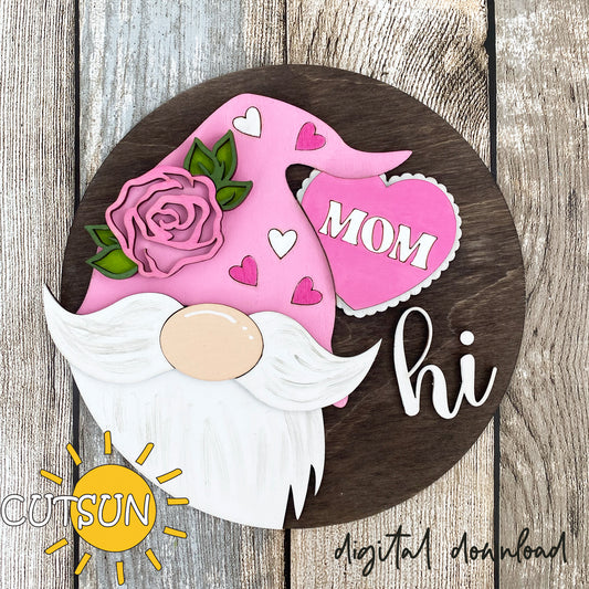 A digital illustration of a pink and white gnome door hanger with a 'Mom' and 'Hi' sign, decorated with a rose and heart shapes.