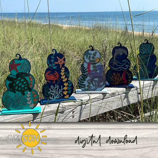 A set of six patterned pumpkins with sea life motifs, displayed on a wooden surface with a blurred background.