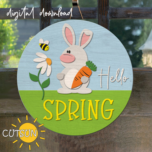 Circular sign with a bunny, carrot, and flower design, featuring the text 'Hello Spring' on a wooden background.