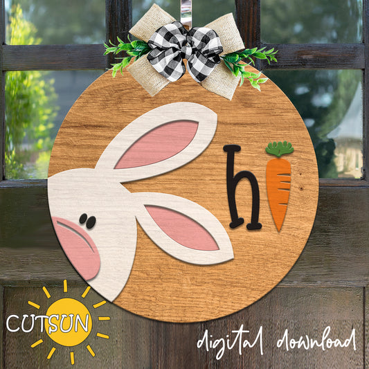 Wooden Easter decoration with bunny ears, carrot, and letter 'h' on a wooden background.