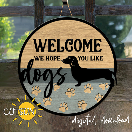 Wooden sign with 'Welcome, we hope you like dogs' text and a dachshund silhouette, featuring paw prints on a wooden background.