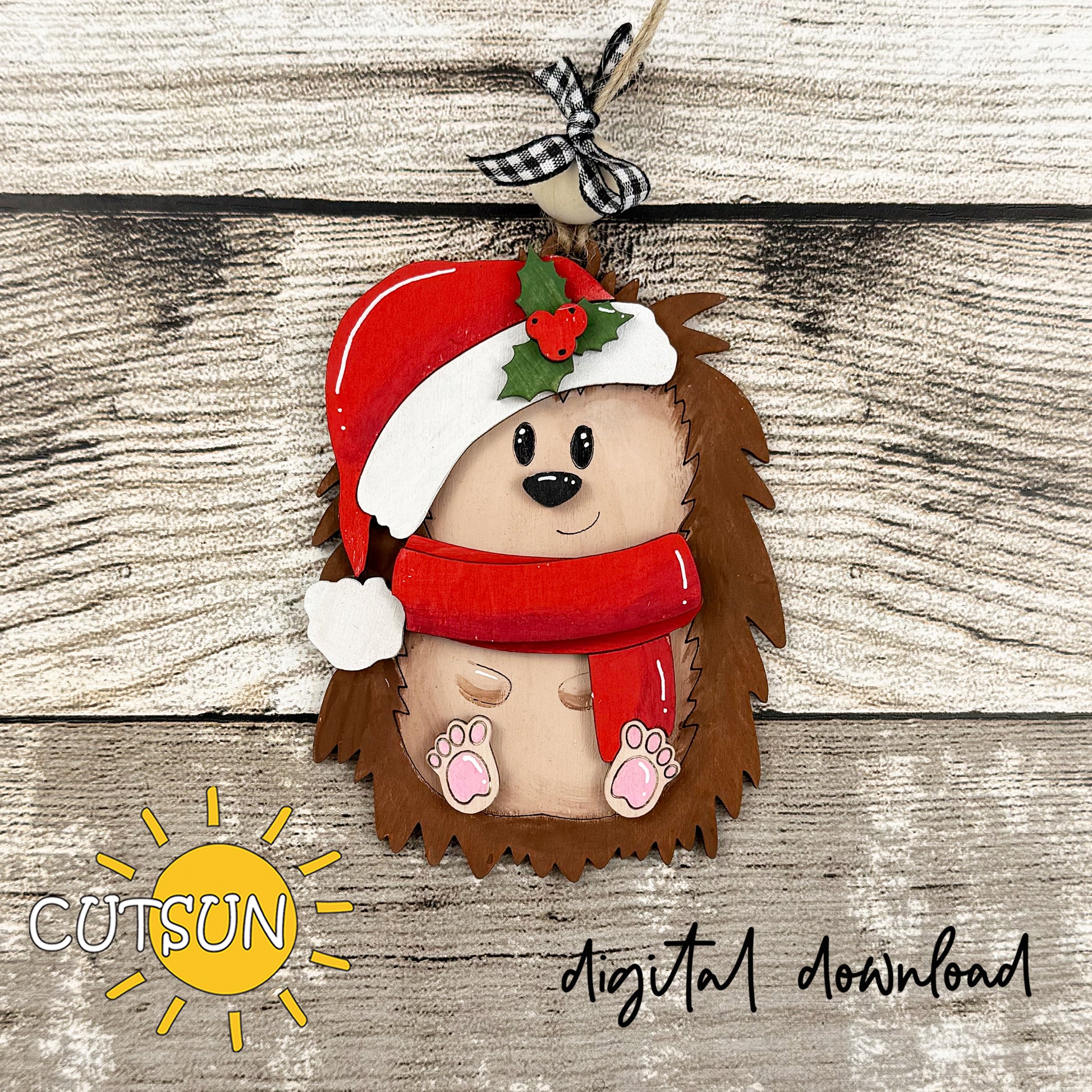 Hedgehog ornament with Santa hat and scarf on a wooden background, featuring the Cutsun brand.