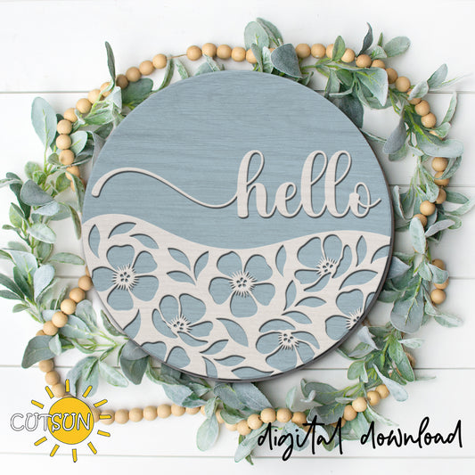 Round hello door hanger with layered white floral cutout design on a soft blue background, displayed on a front door as laser cut decor.