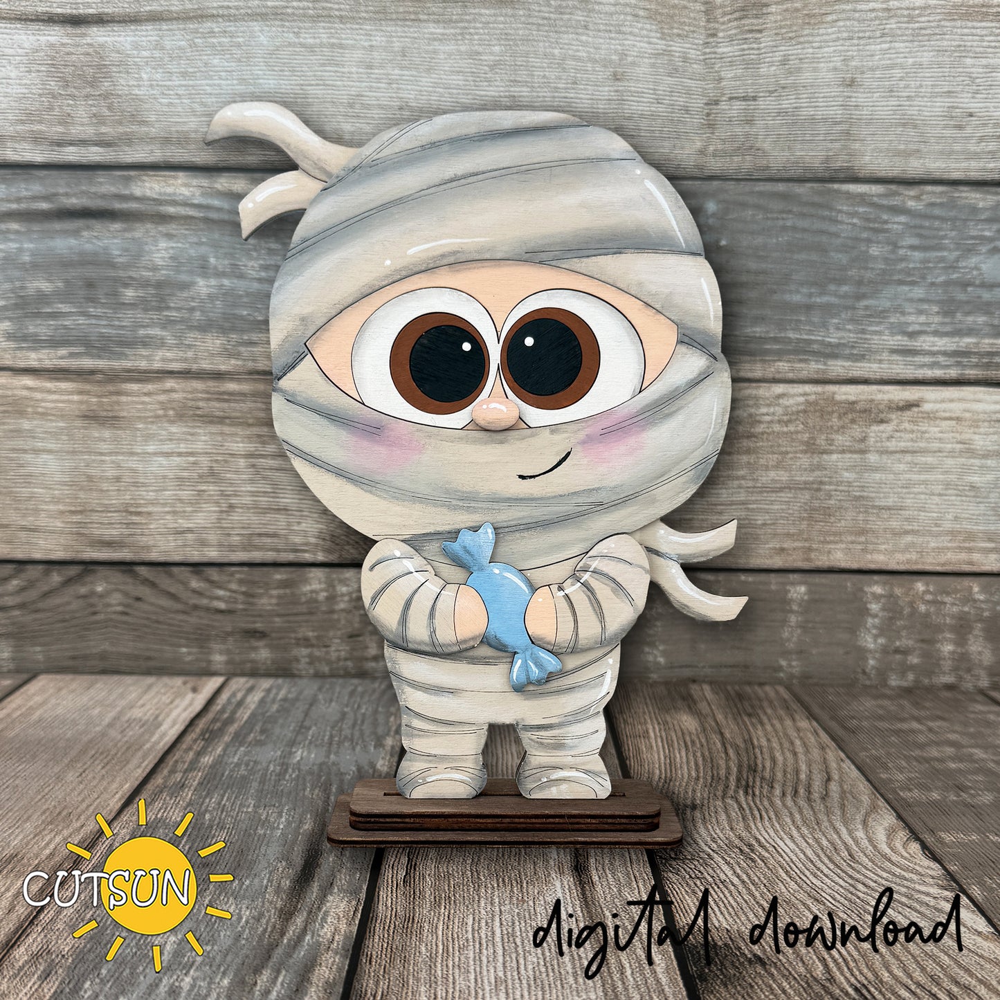 Cute layered Halloween mummy shelf sitter laser cut file featuring a cartoon mummy holding candy, designed for freestanding seasonal shelf decor.