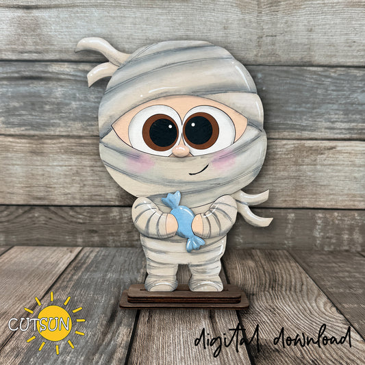 Cute layered Halloween mummy shelf sitter laser cut file featuring a cartoon mummy holding candy, designed for freestanding seasonal shelf decor.