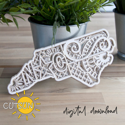 Decorative laser-cut paper cutout of a bear with intricate patterns on a wooden surface, featuring the Cutsun logo.