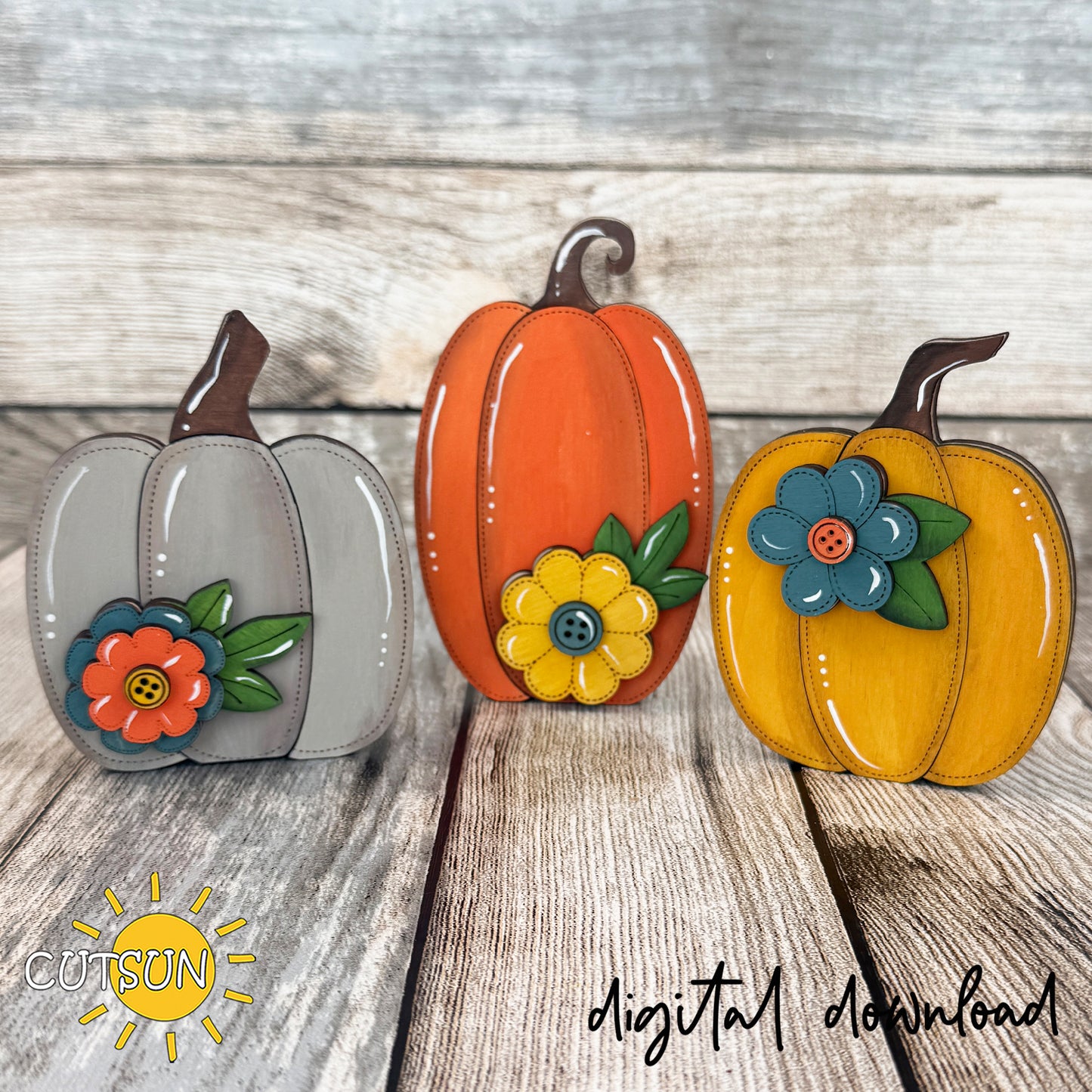 Set of three layered wooden pumpkin shelf sitters in gray, orange and mustard yellow, featuring stitched details, button-centered flowers and rustic farmhouse fall colors.