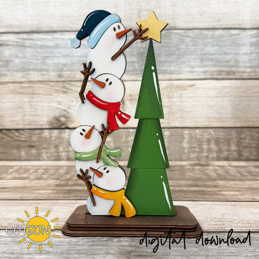 Layered wooden snowman shelf sitter with four snowmen in colorful scarves beside a green Christmas tree topped with a gold star, on a compact brown base.