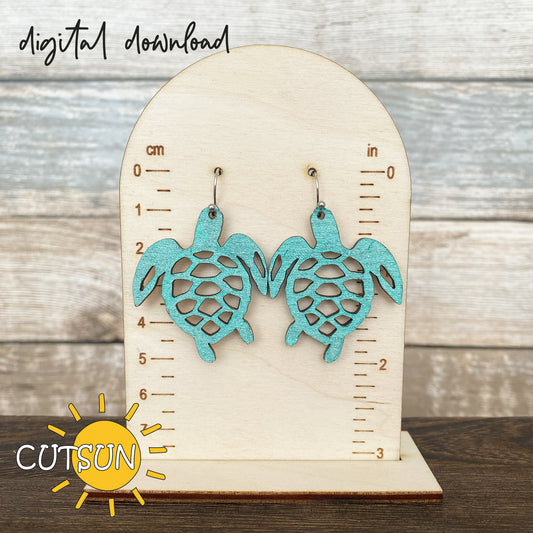 Pair of turquoise sea turtle earrings displayed on a wooden measurement stand, perfect for laser-cut jewelry crafts.