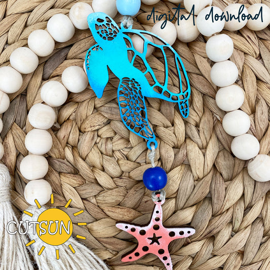 Laser-cut sea turtle and starfish charm with wooden beads and tassels, styled as a coastal-themed car or home decoration.
