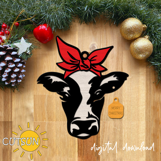 Decorative cow ornament with a red bow and 'Merry Christmas' tag on a wooden surface with Christmas decorations.