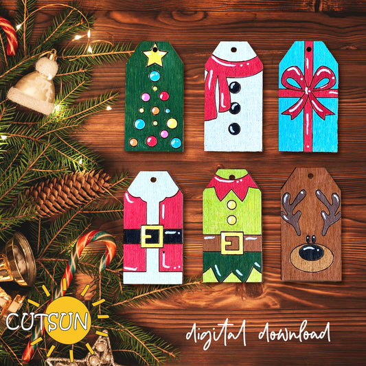 Set of Christmas-themed wooden tags on a wooden surface with tree branches and lights.